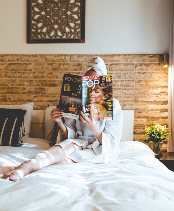 מלון גרנד ויסטה - אשה קוראת עתון בחדר על המיטה